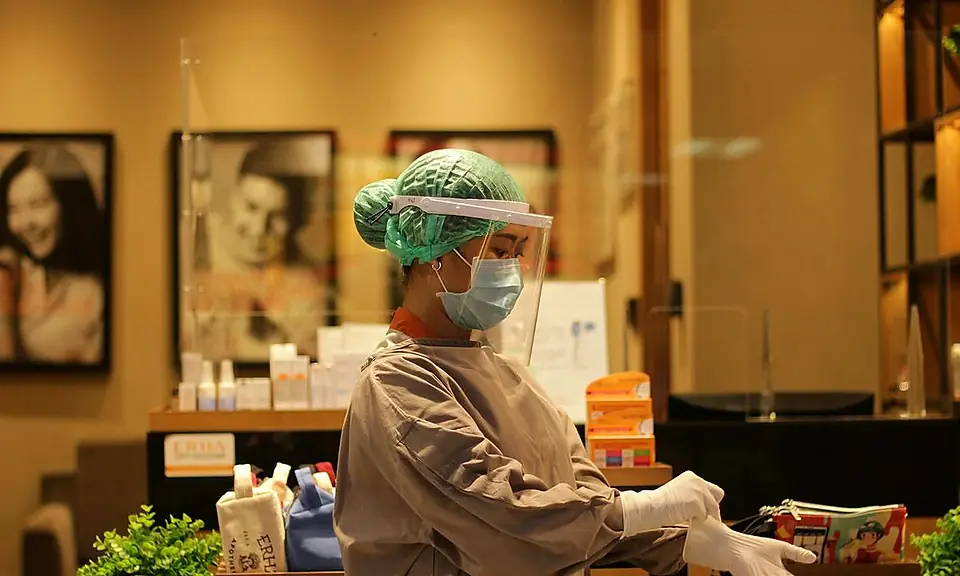 Nurse in PPE putting on gloves at a clinic station